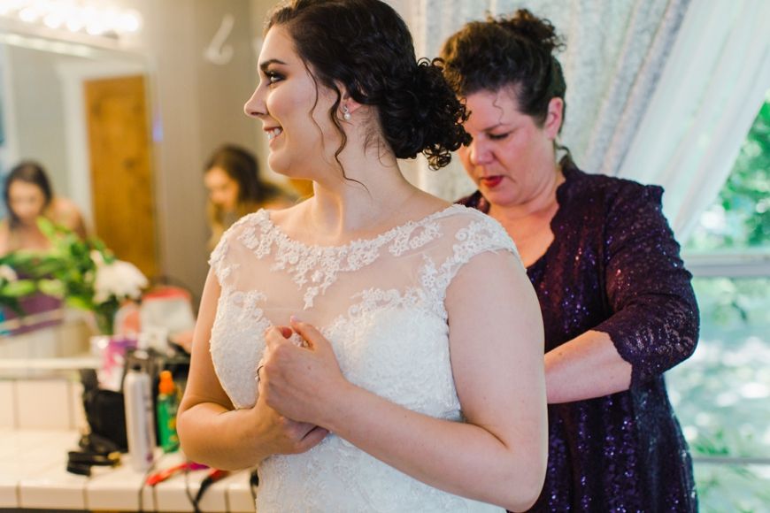 Final adjustments being made to a beautiful white lace wedding dress.