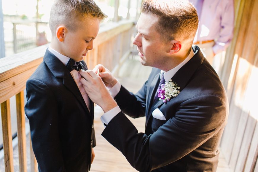 Formal bow tie adjustment scene on a wooden porch with natural lighting.