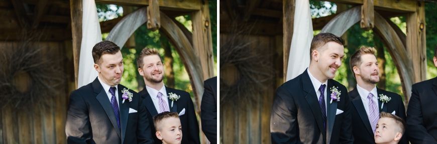 Wedding party members standing under a rustic wooden pavilion during an outdoor ceremony.