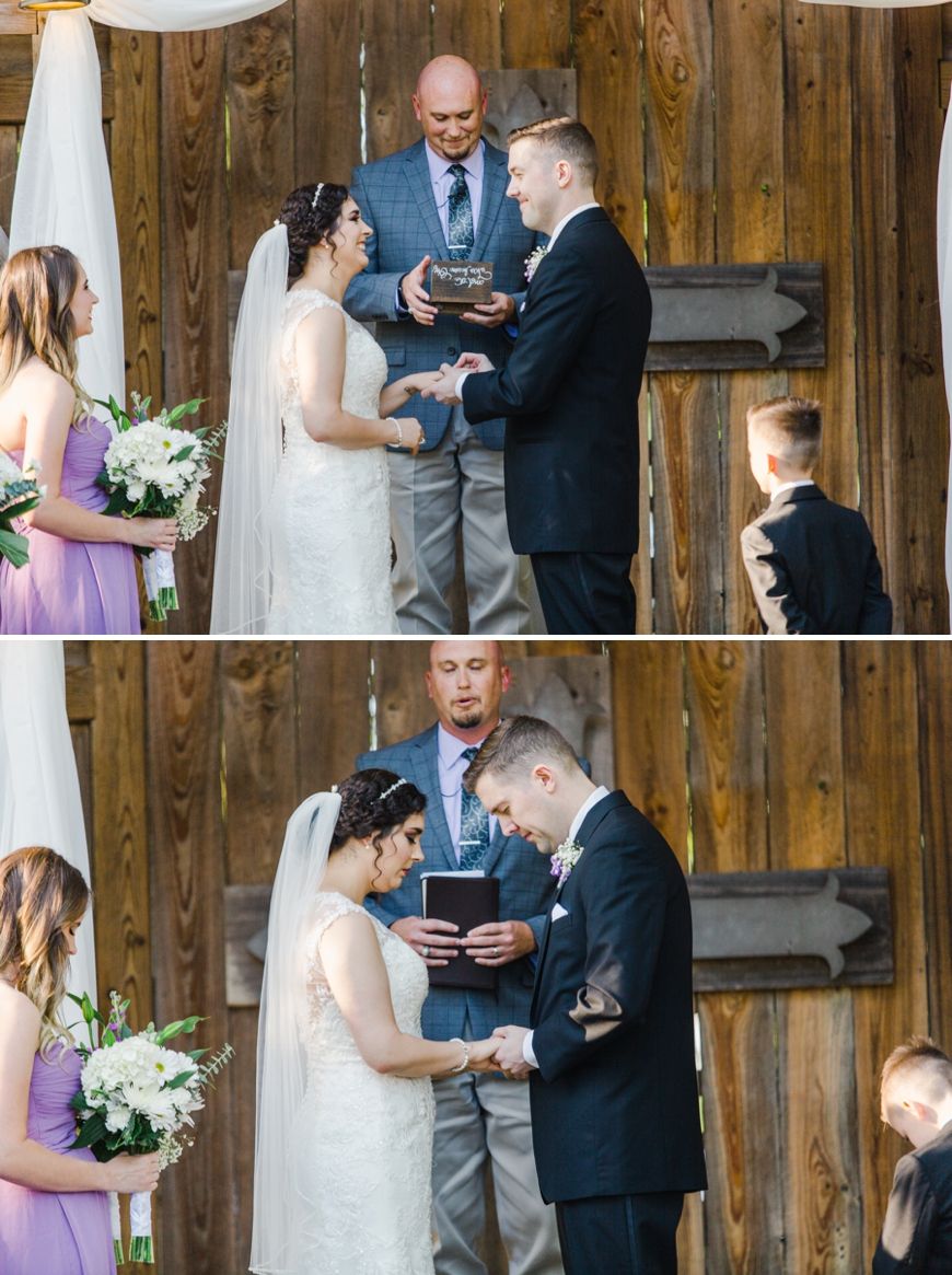 An intimate wedding ceremony takes place under a rustic wooden pavilion with white draping.