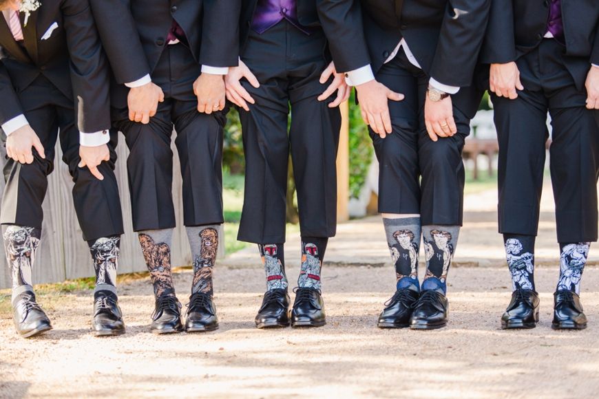 Groomsmen show off their fun matching socks during group photo at wedding.
