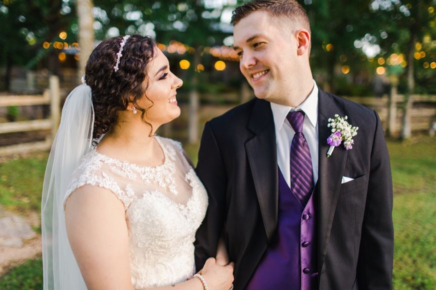 A romantic outdoor wedding portrait of a couple with beautiful bokeh lighting and rustic wood fencing.