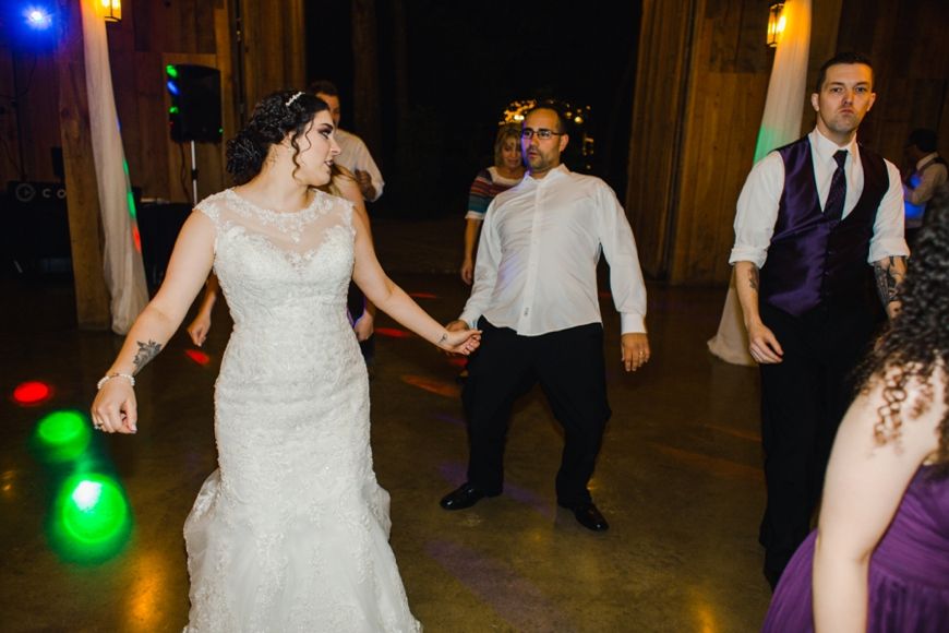 Wedding guests and bride dancing at reception with colorful disco lights.