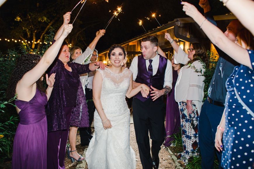 Wedding party holding sparklers during outdoor nighttime celebration.