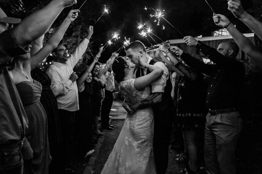 Black and white wedding sparkler exit photo with guests waving sparklers.