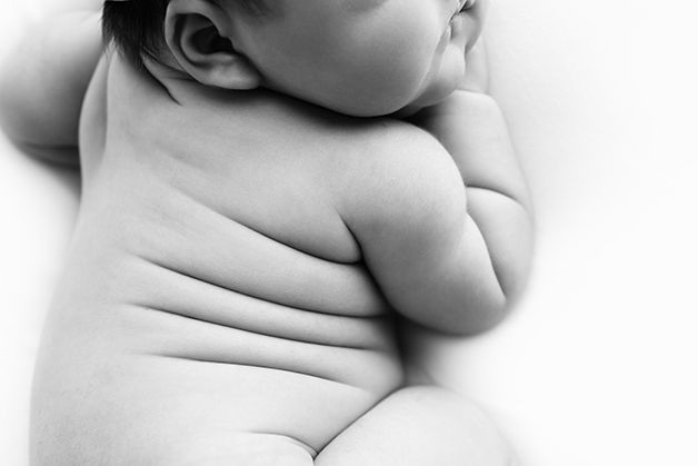 Black and white image of newborn baby girl's back rolls.