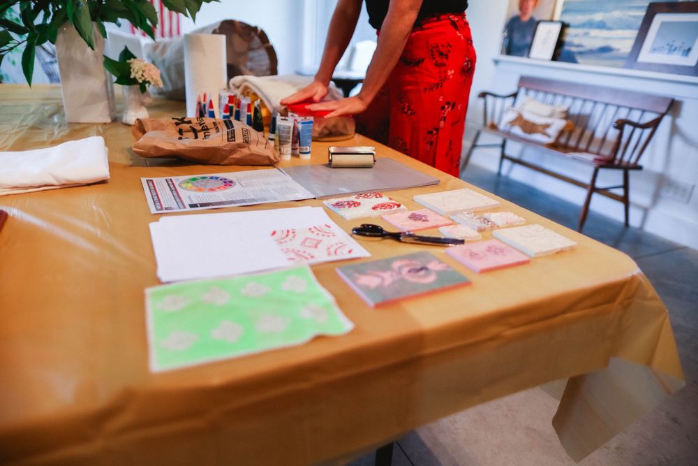 Art supplies and materials arranged on wooden tables in a bright gallery space.