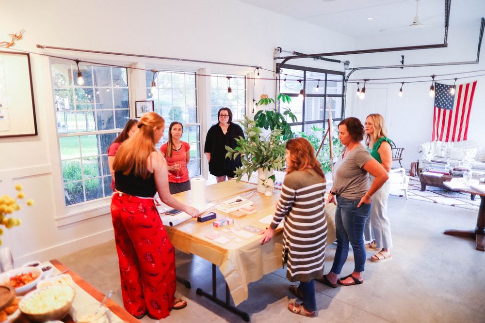 Gallery space with artwork displayed on walls and people gathering for an event.