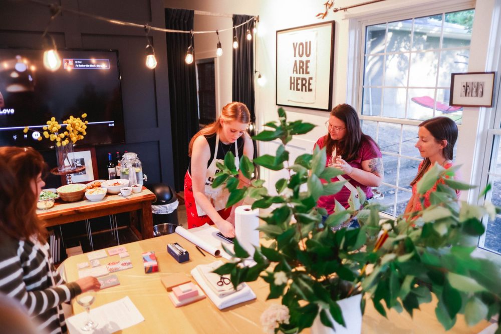 People gathered around a long table in an art gallery for a creative workshop.