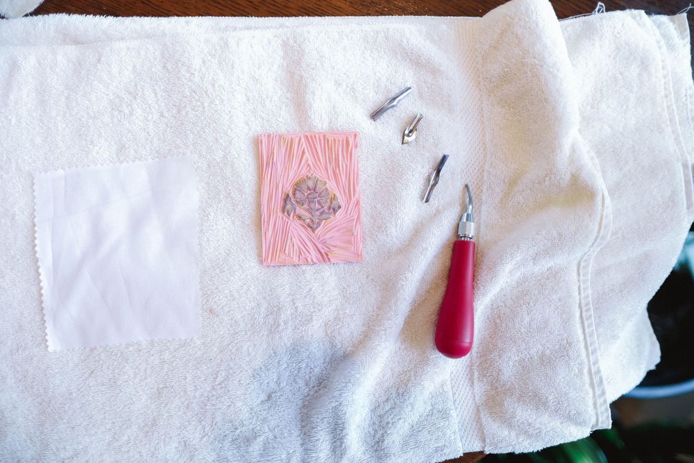 Art supplies and papers are arranged on white tables during a creative workshop session.