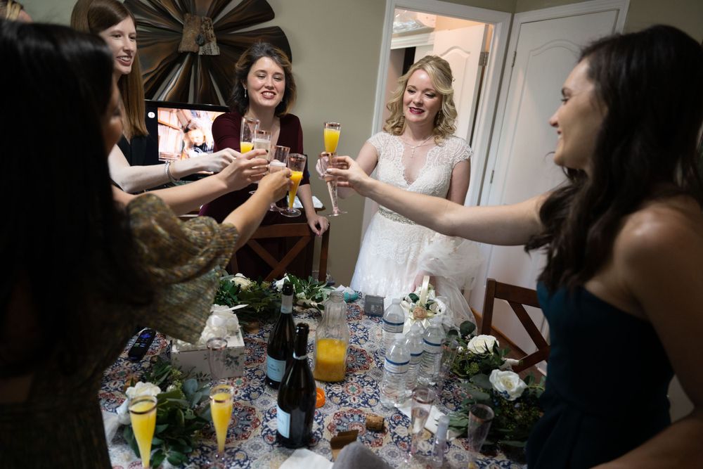 Wedding party toasts with mimosas during pre-ceremony preparations.