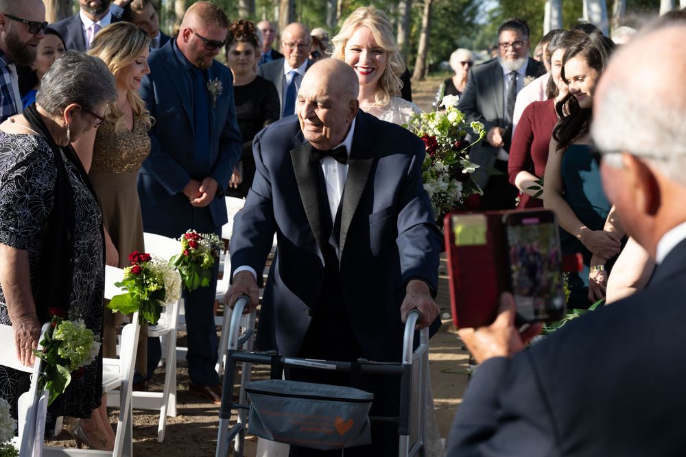 Guest using walker approaches seating area during outdoor wedding ceremony.