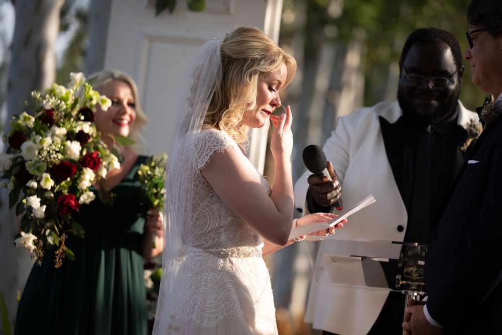 Emotional moment during outdoor wedding ceremony with bride reading vows.