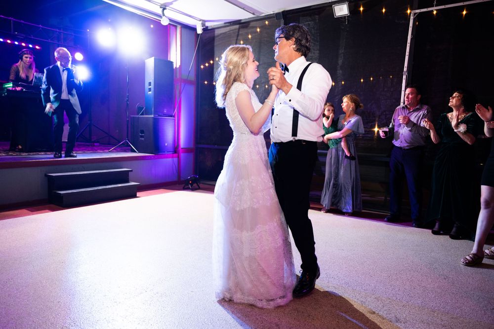 Romantic first dance at wedding reception with dramatic blue stage lighting.