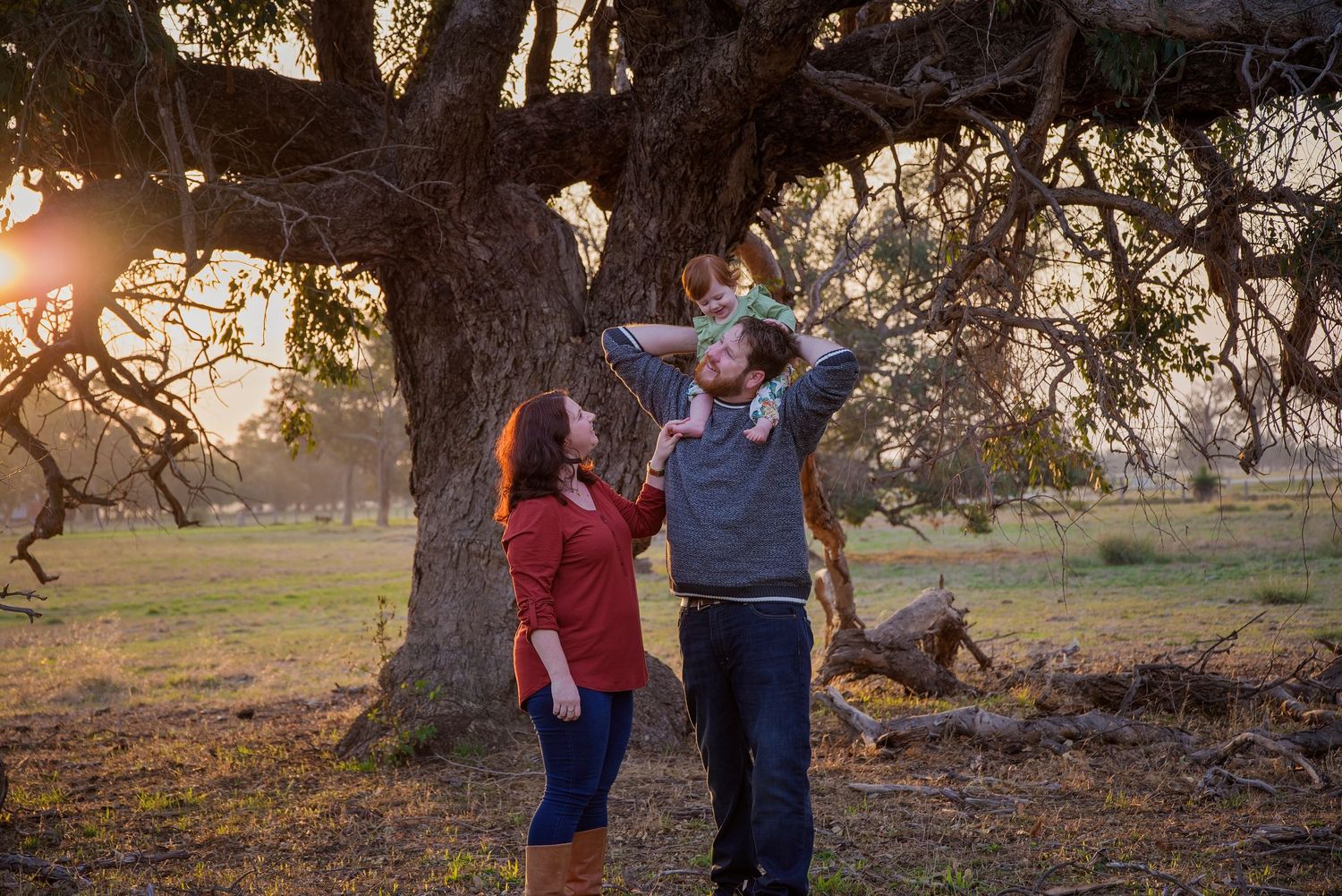 family smiling at eachother under tree