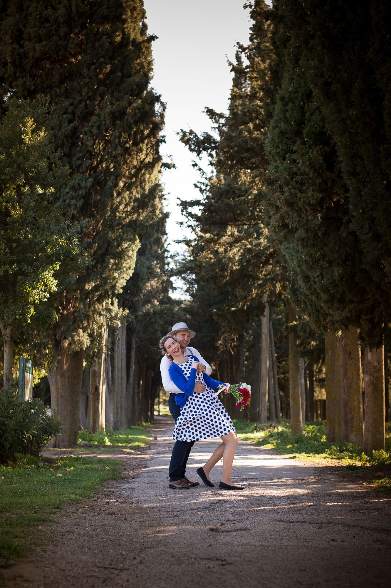 couple dancing among high trees in tatoi estate in athens during their pre-wedding photoshoot
