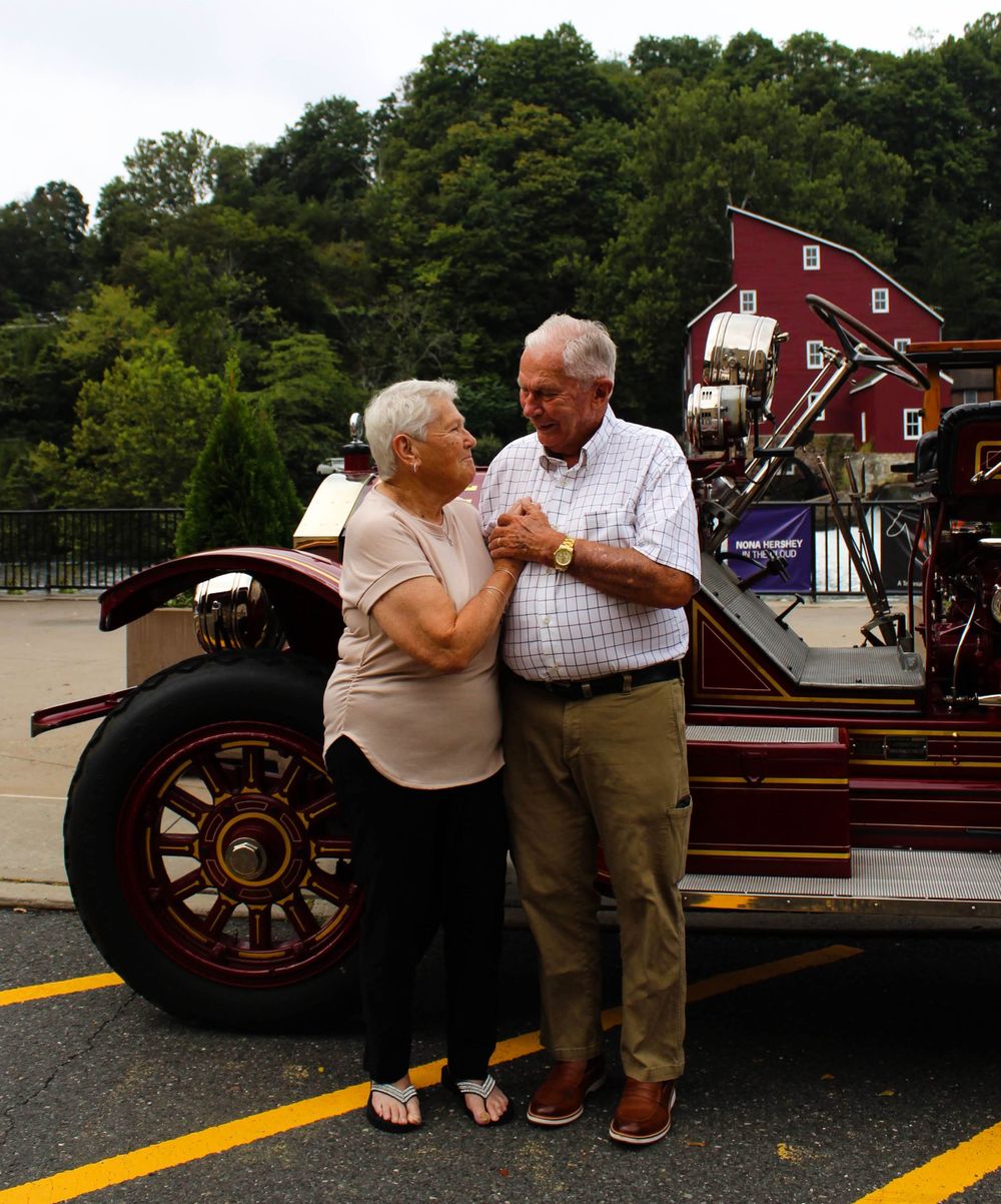 A couple shares an intimate dance moment beside a vintage fire truck.