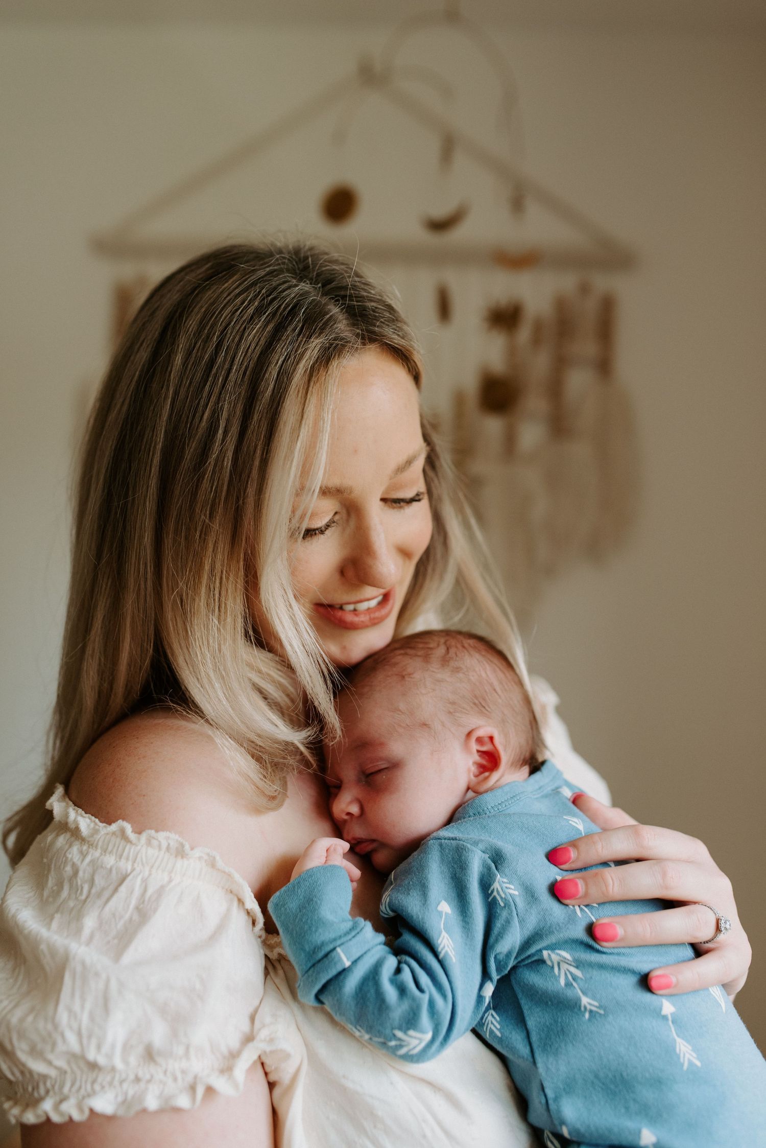 Tender moment between parent in white lace and sleeping baby in blue.