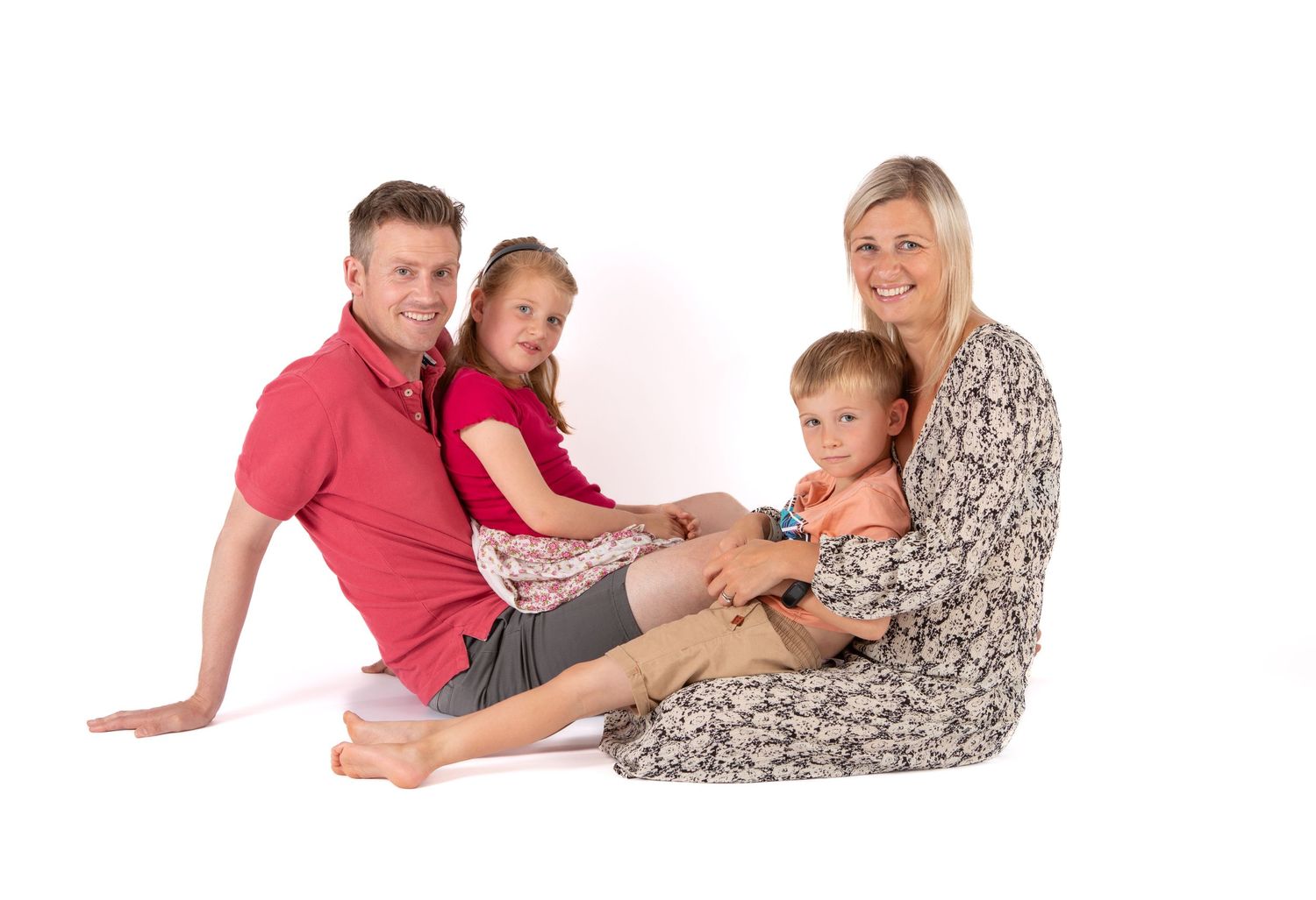 Family of four poses casually together on white backdrop in coordinated outfits.