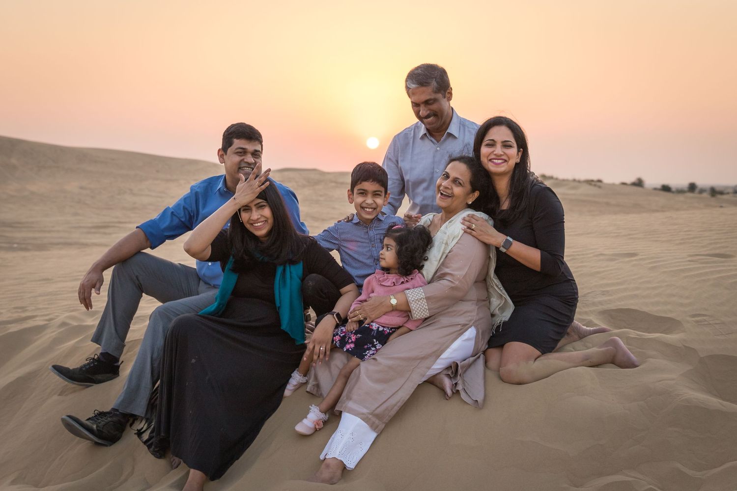 Family posing on sand dunes in dark and blue clothes in Dubai desert