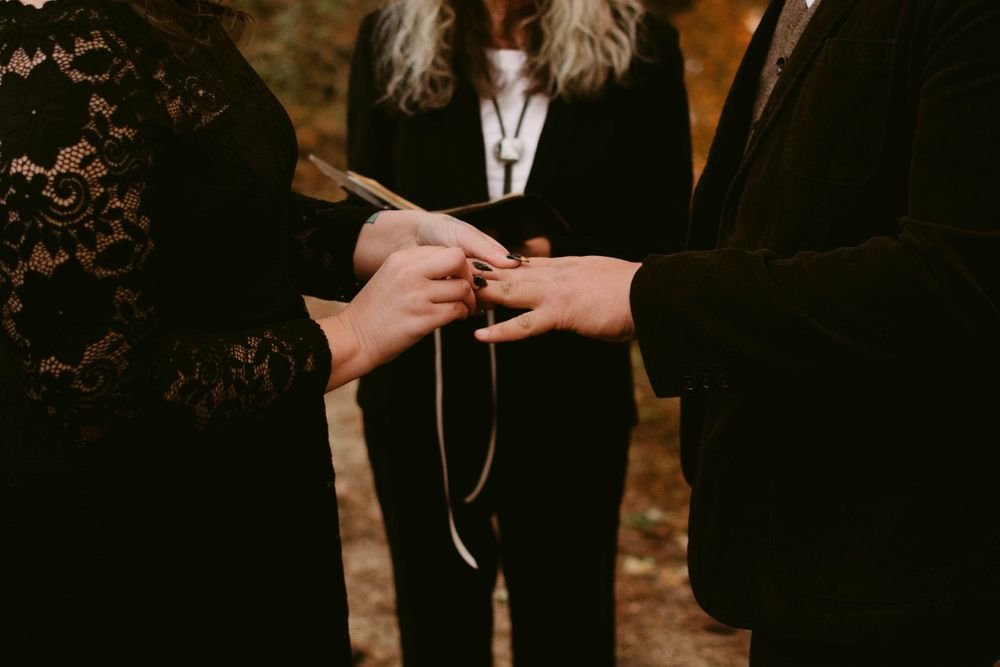 Close-up of ring exchange during forest wedding ceremony.