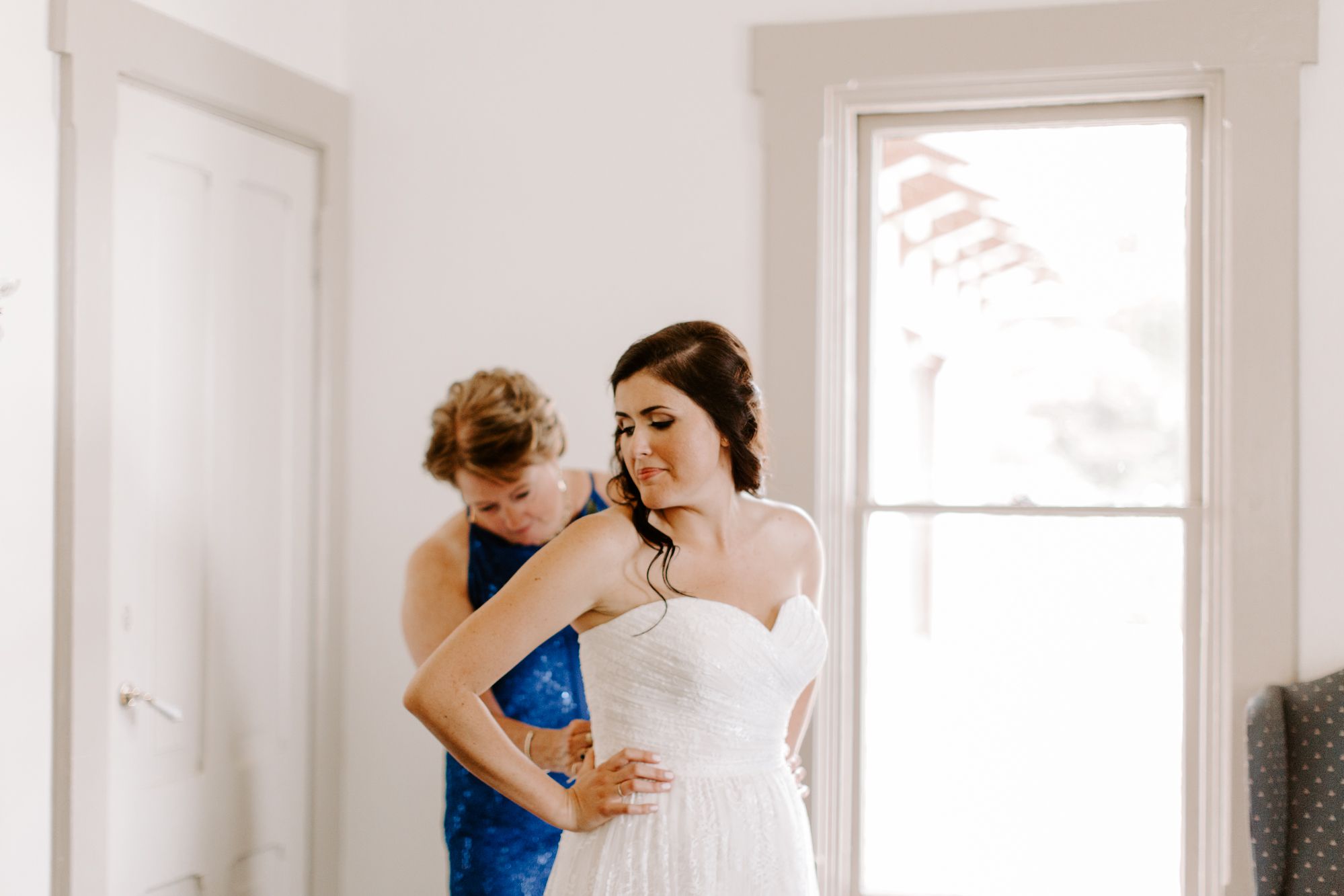 Interior wedding preparation scene with soft natural light streaming through large windows.