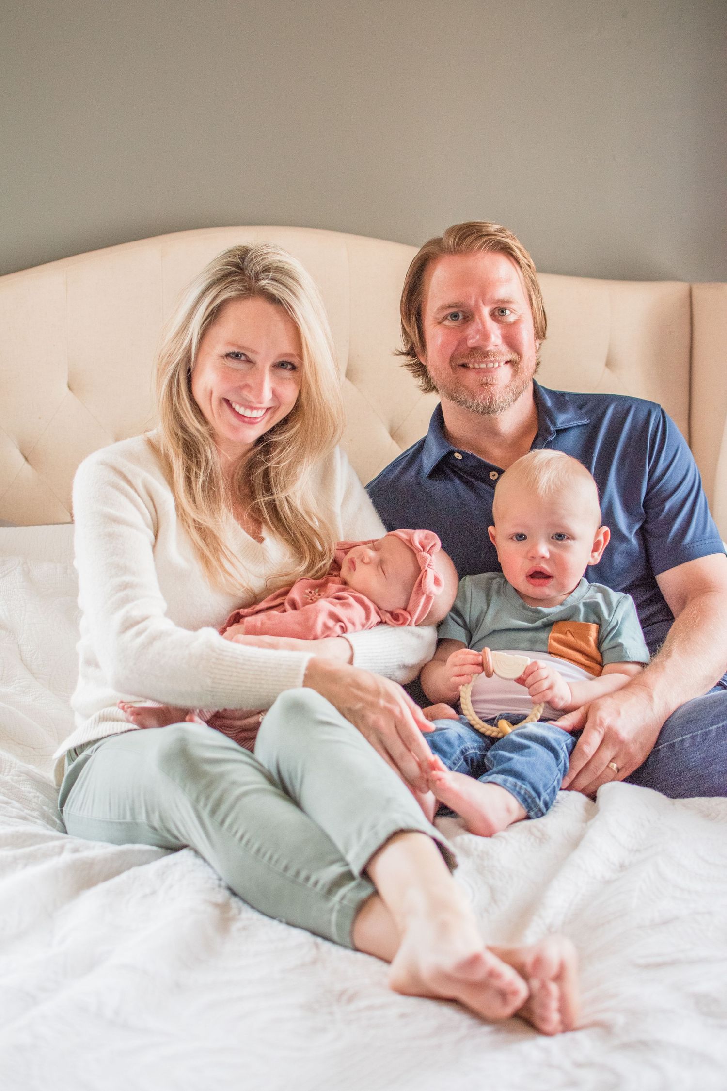 Family relaxing together on cream colored headboard bed in casual attire.
