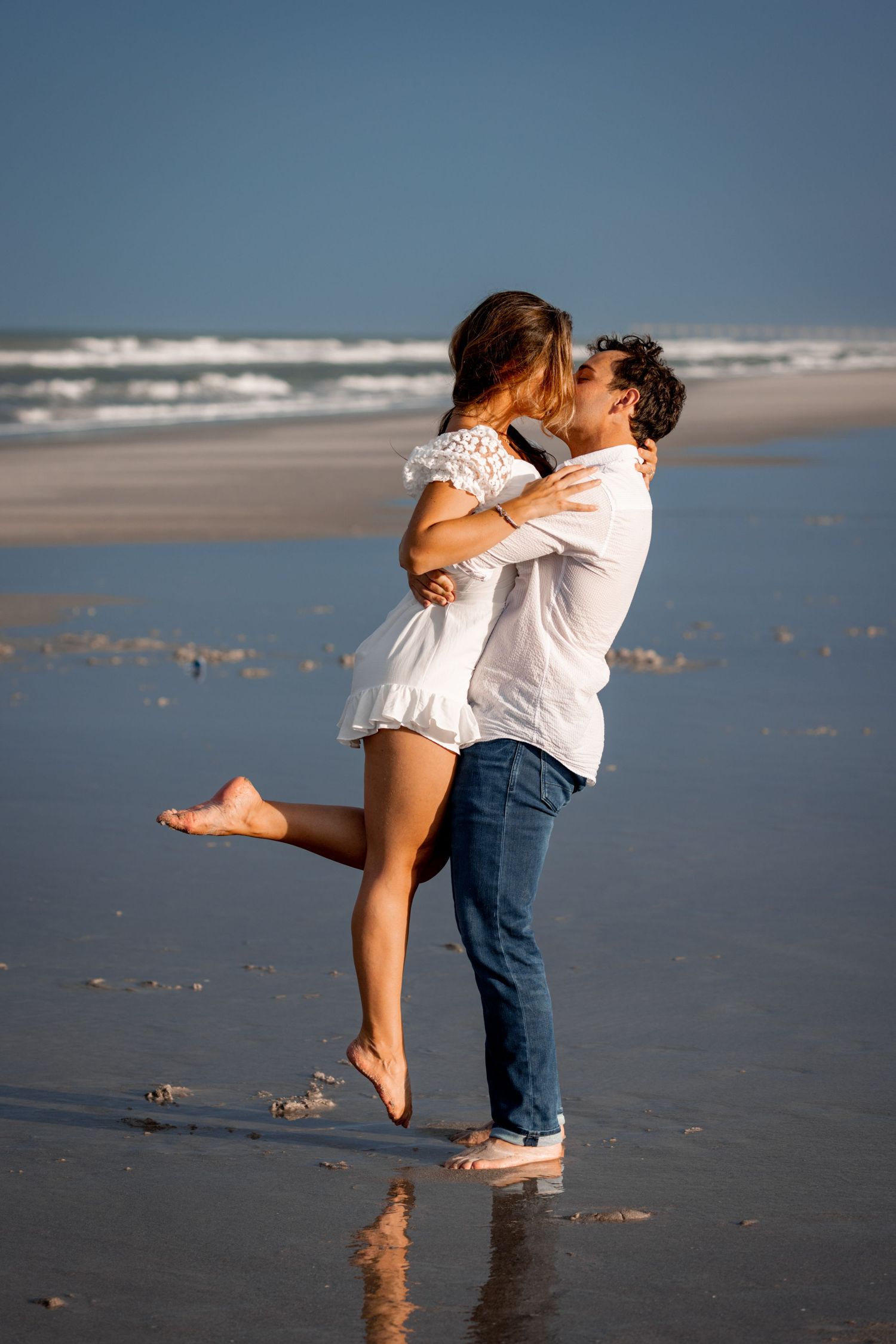 Romantic beach scene with couple embracing at the ocean's edge.