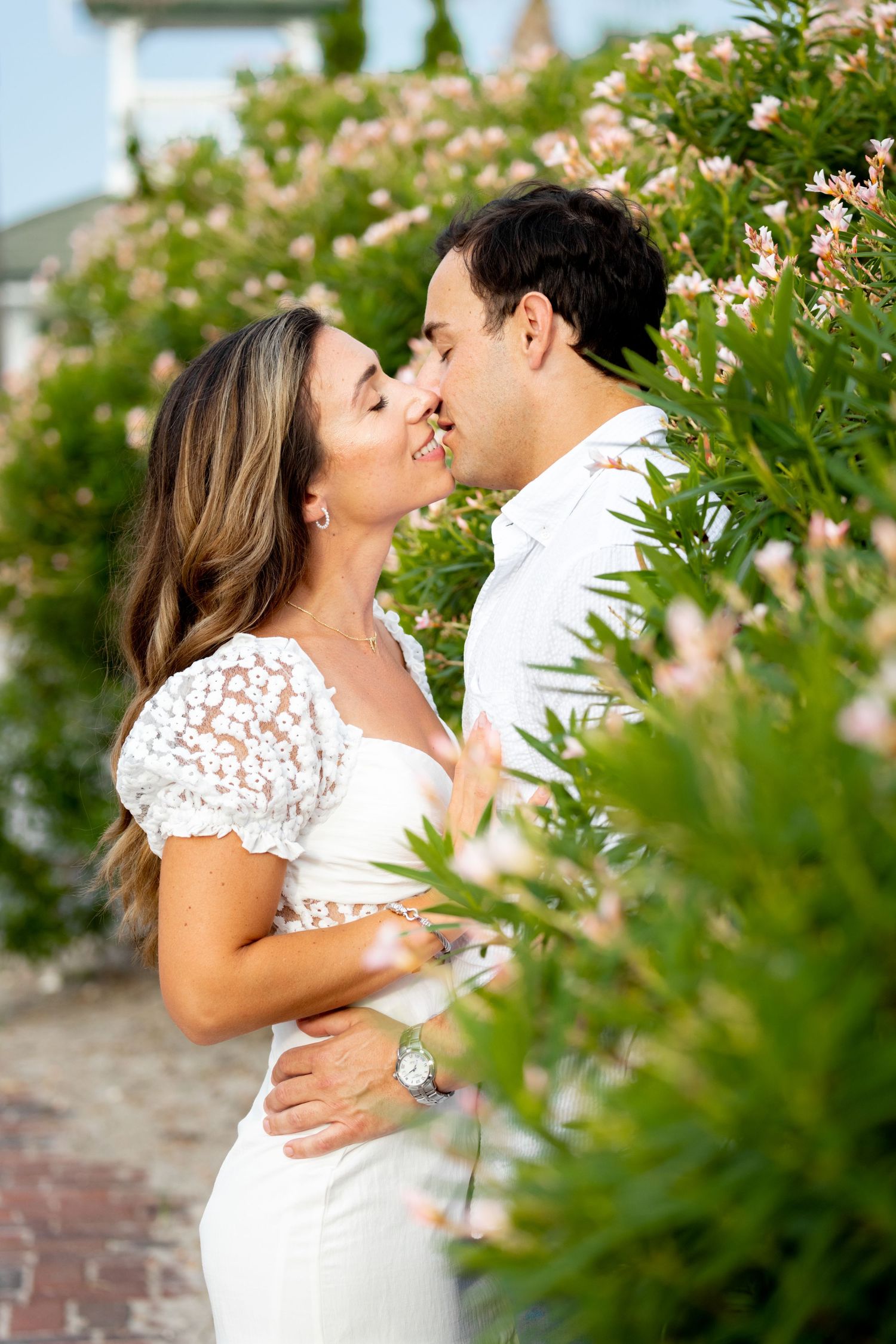 Romantic moment captured among pink blooming flowers in a garden setting.
