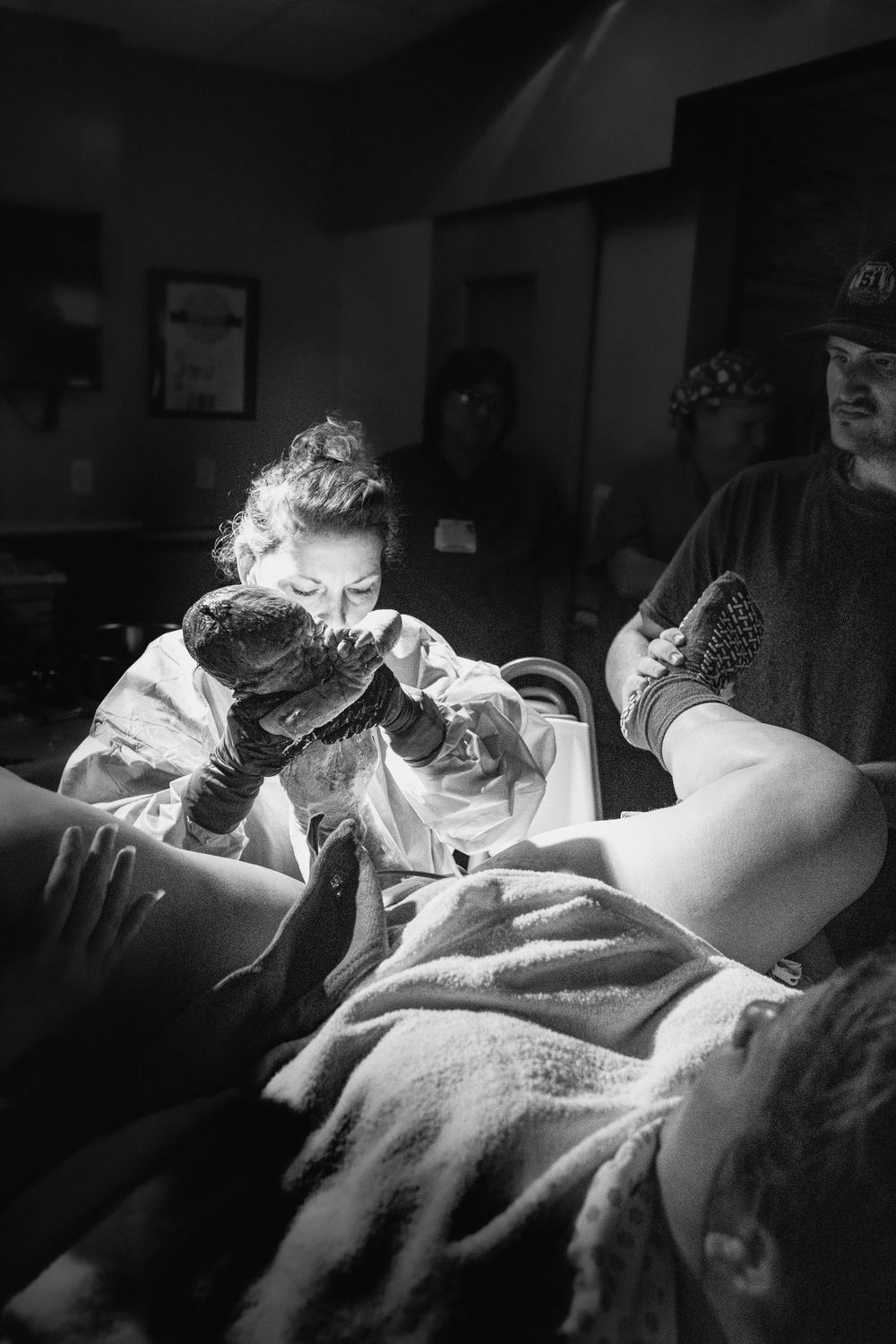 Black and white image of medical care being provided in dimly lit room.