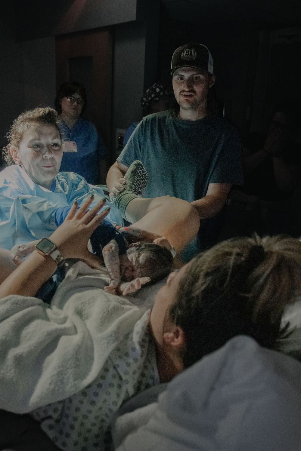 Medical staff attending to a patient in a hospital bed during what appears to be a delivery or medical procedure.