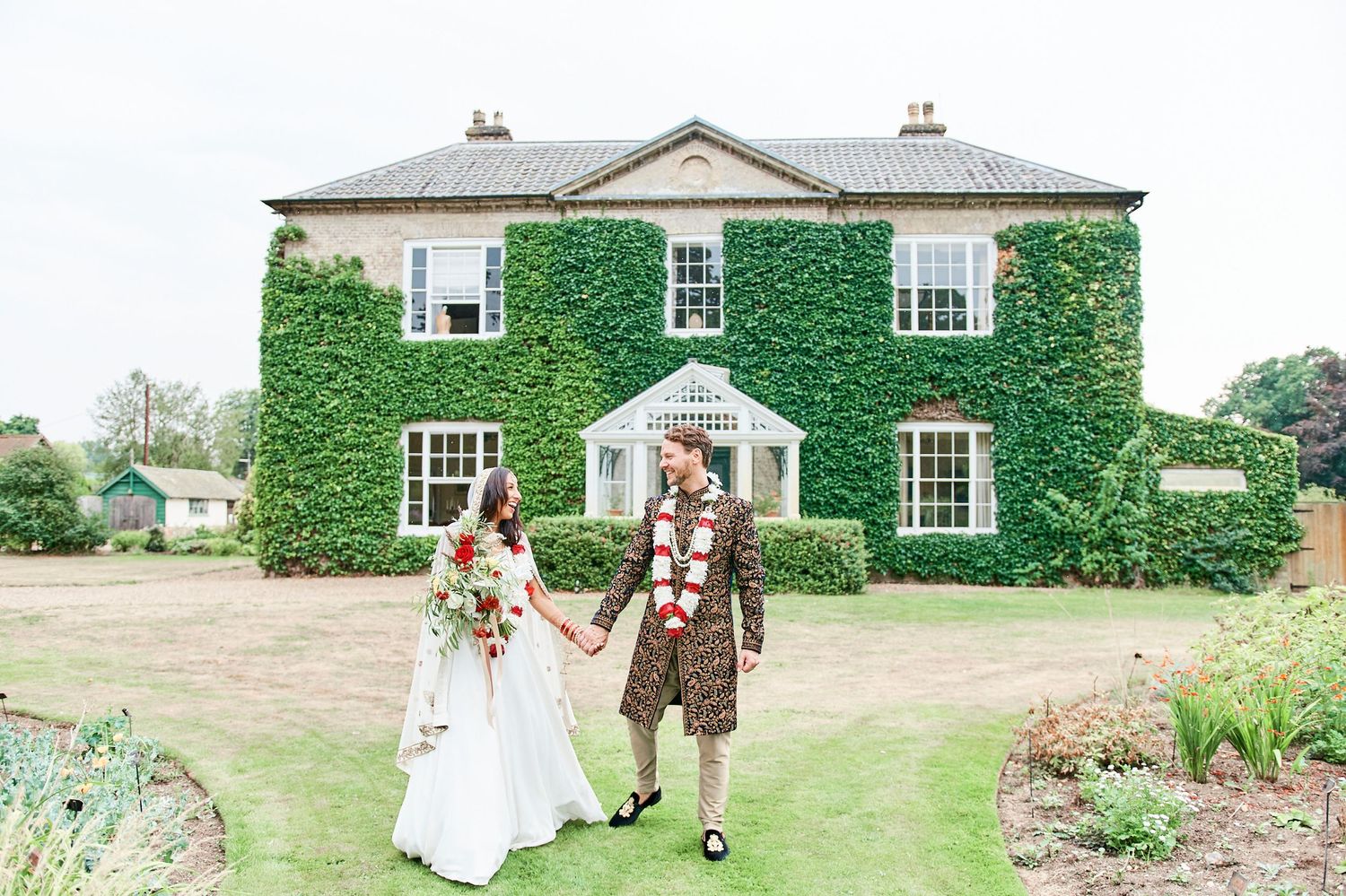 bride and groom holding hands in gardens at Bressingham Hall by award winning Norwich wedding photographer Faye Amare