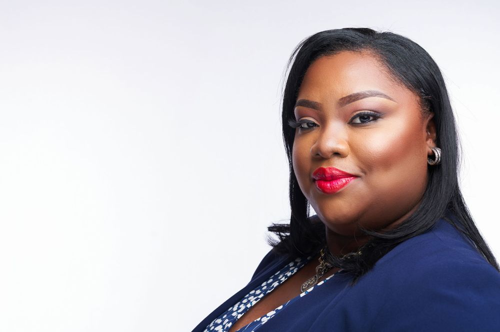 Professional portrait of a woman in blue blazer with red lipstick against white background.