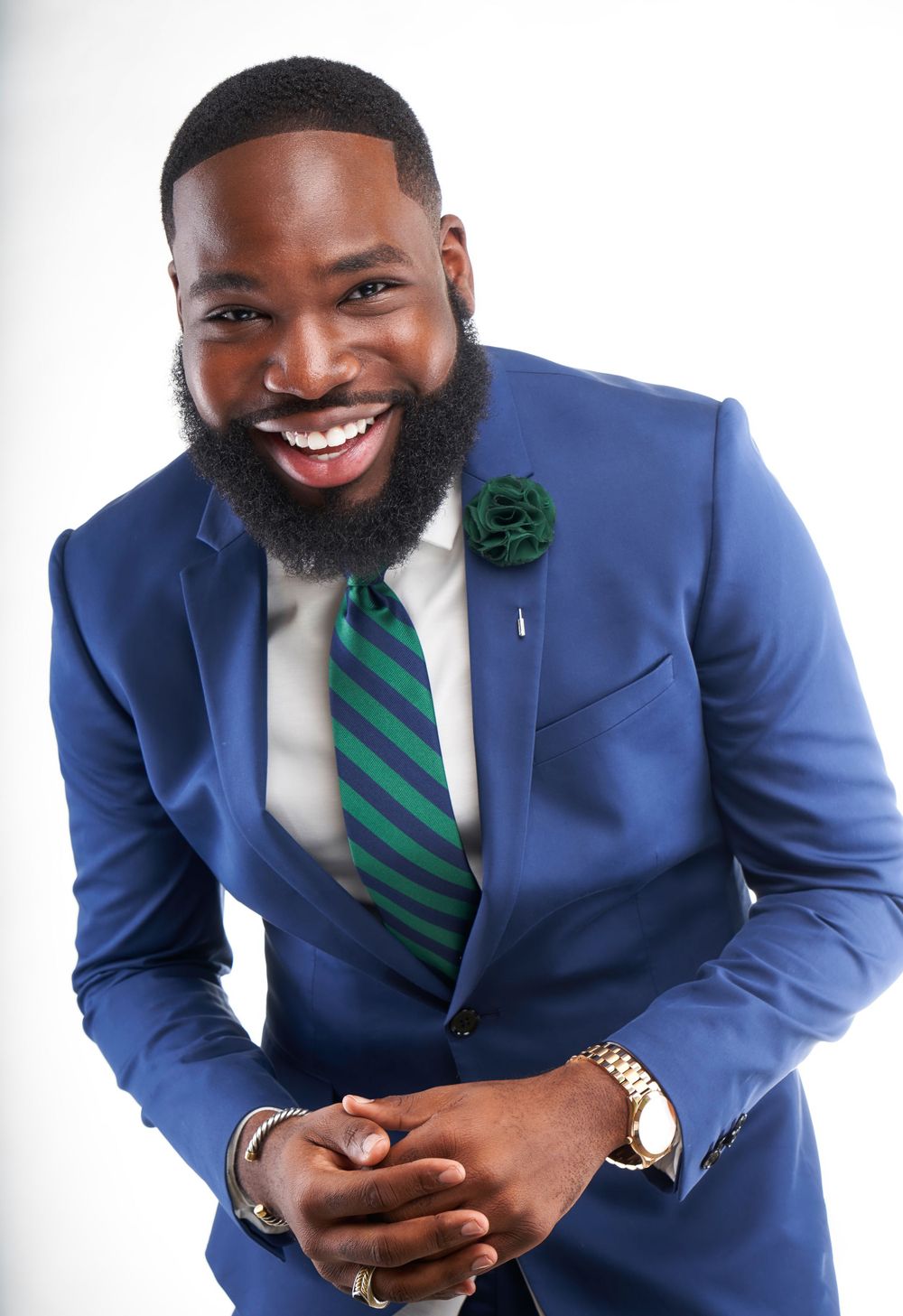 Business professional in blue suit with striped green tie and beard smiling warmly.