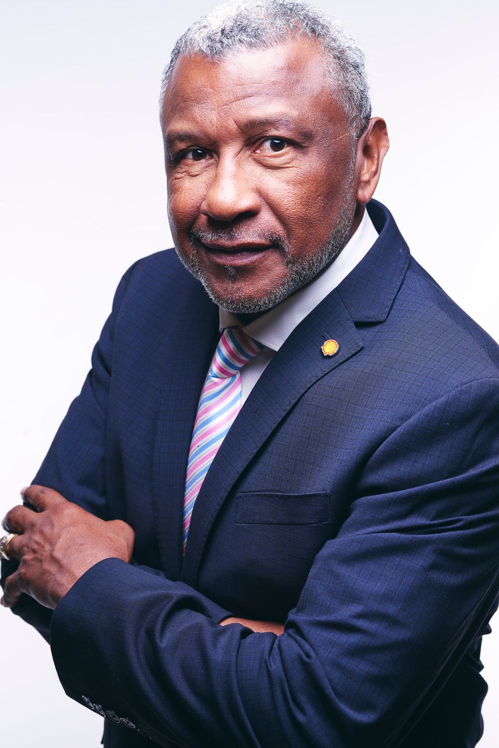Distinguished mature executive in navy suit with striped tie against white backdrop.