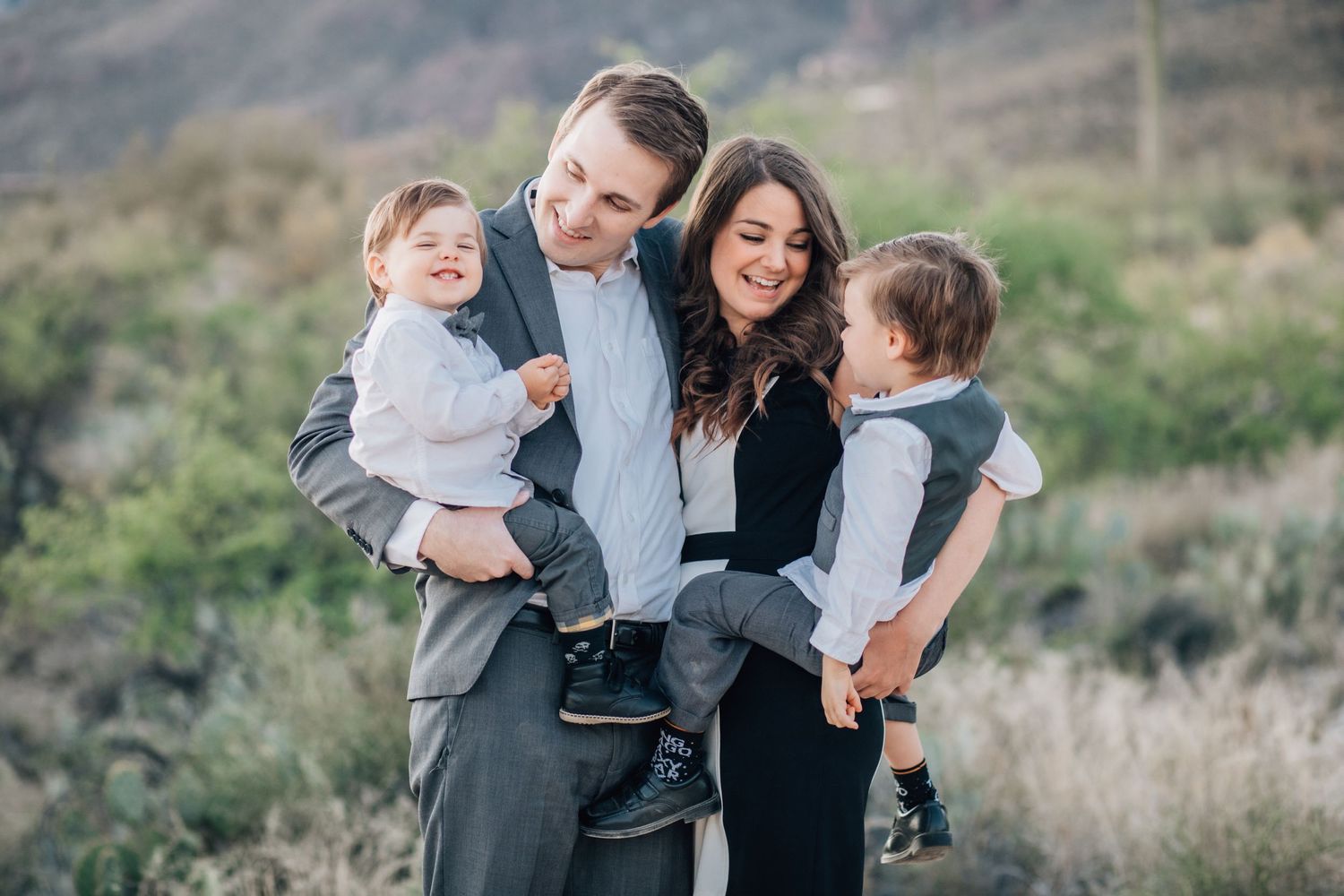 Tucson family photography of parents holding their two young boys in the desert with soft, natural lighting.