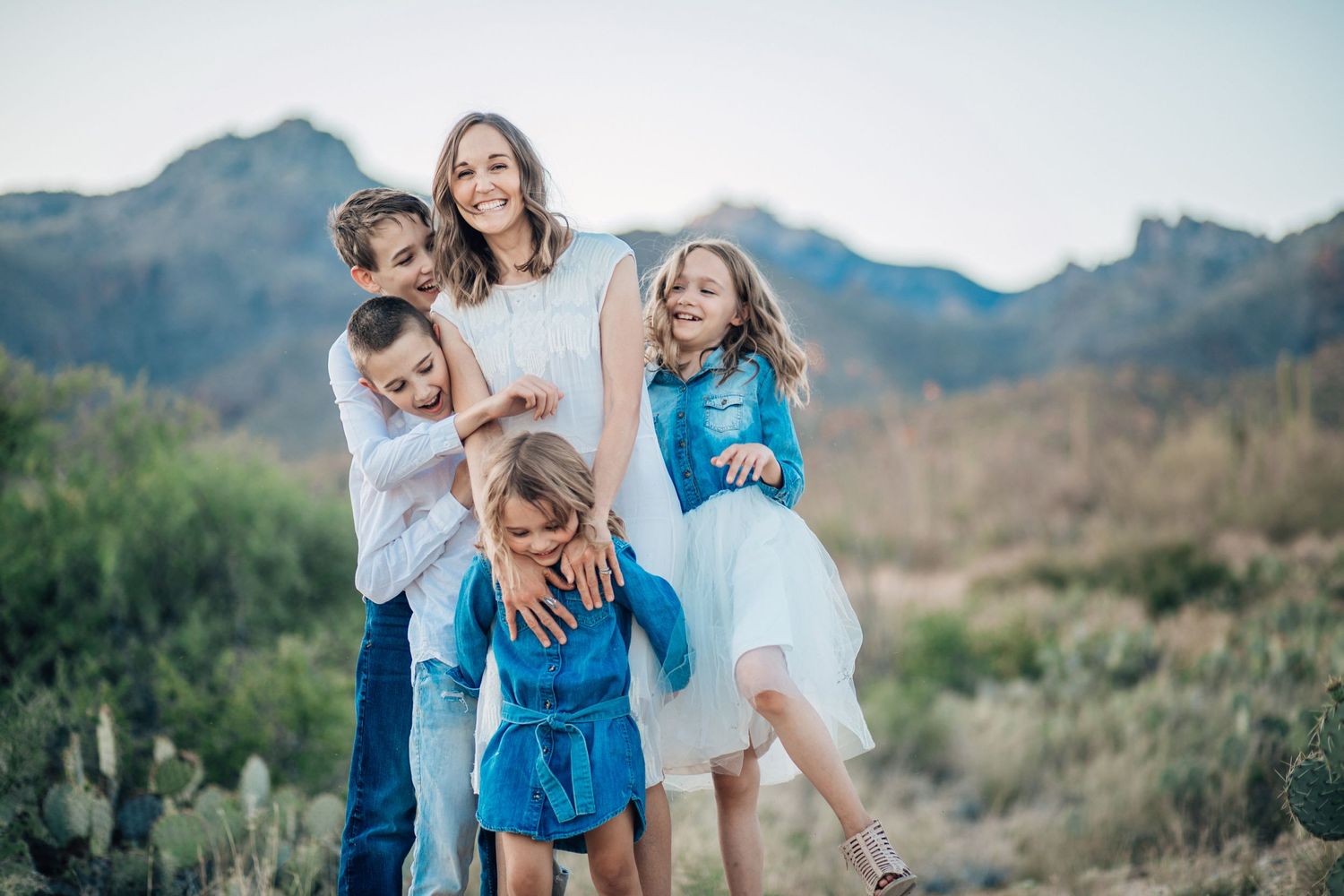 Tucson family photo of four sisters smiling together in the desert with mountains in the background.