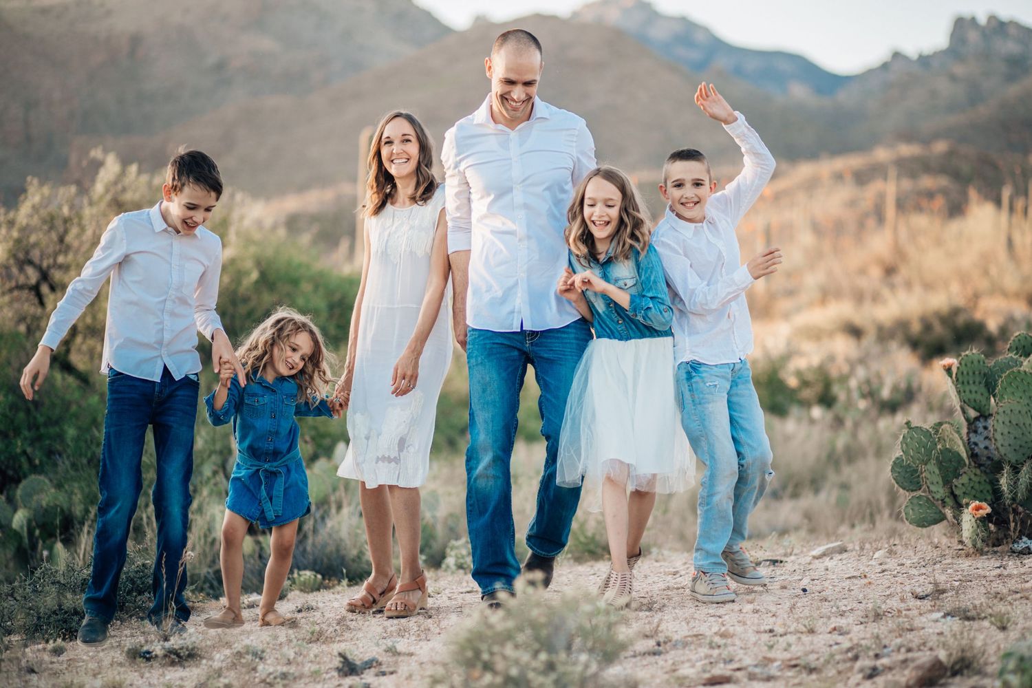 Tucson family portrait of parents and children standing in the desert at sunset with warm natural light.