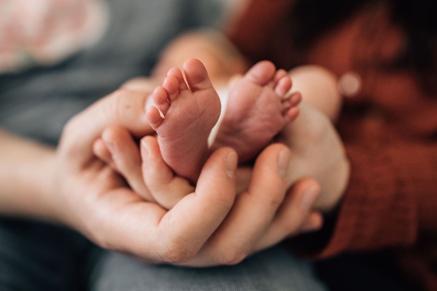 Tucson newborn photography close-up of tiny baby feet resting in the parents’ hands.