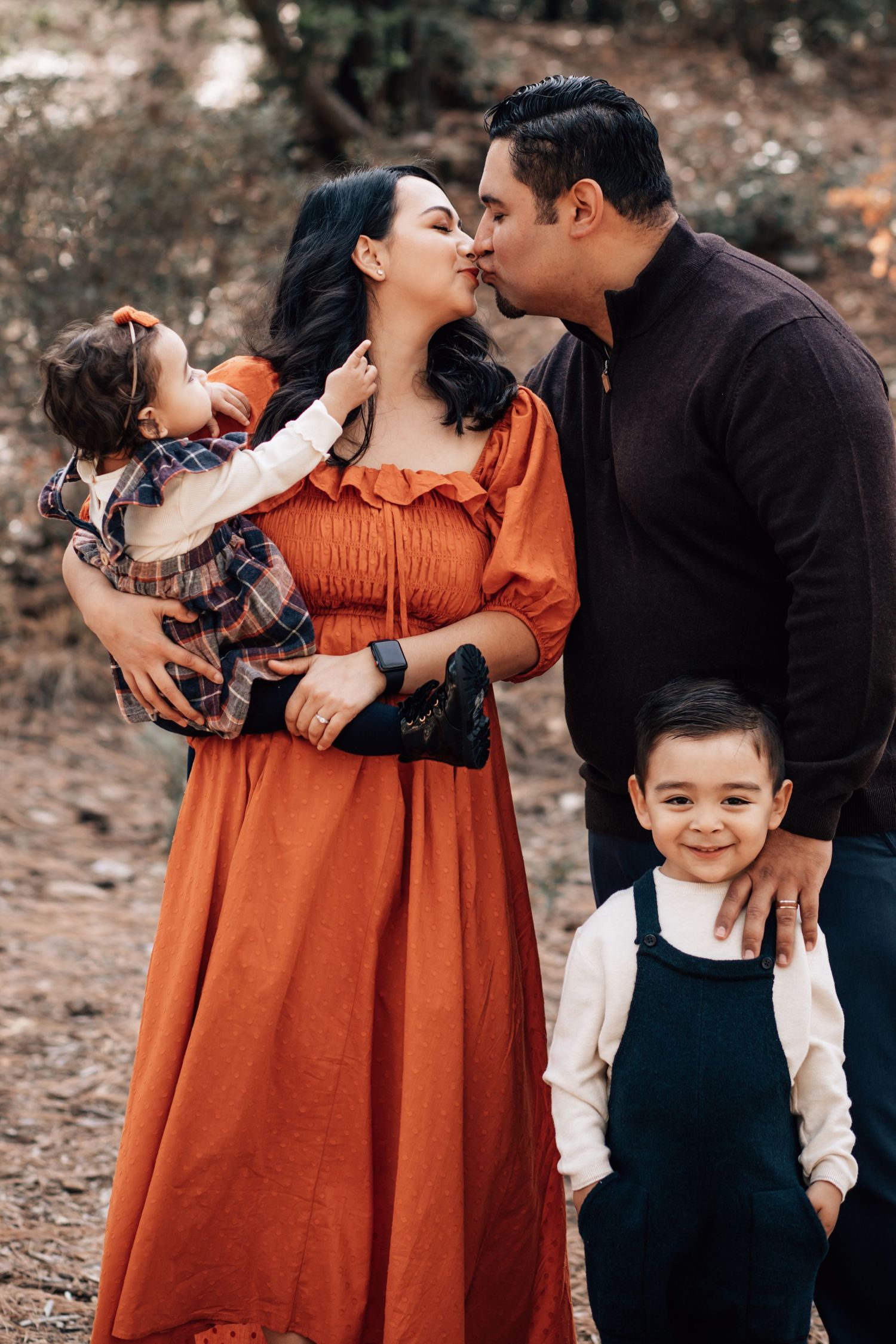 Tucson family portrait of parents holding their young children in a forest Mr. Lermmon area with soft golden lighting.