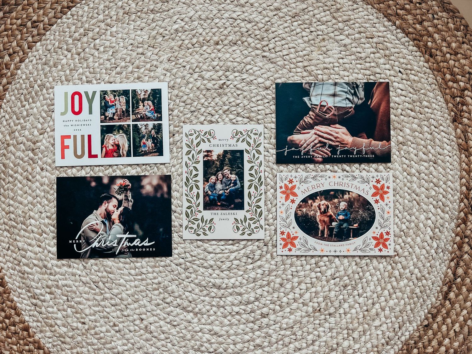 5 different holiday card designs from Basic Invite showcased on a braided rug