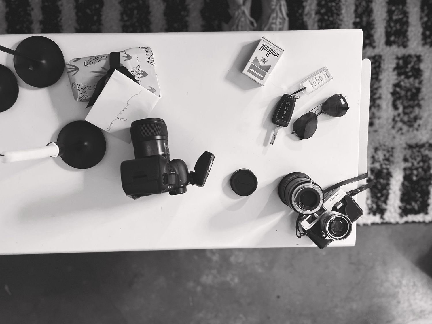 Overhead view of camera equipment and lenses arranged on a white surface.