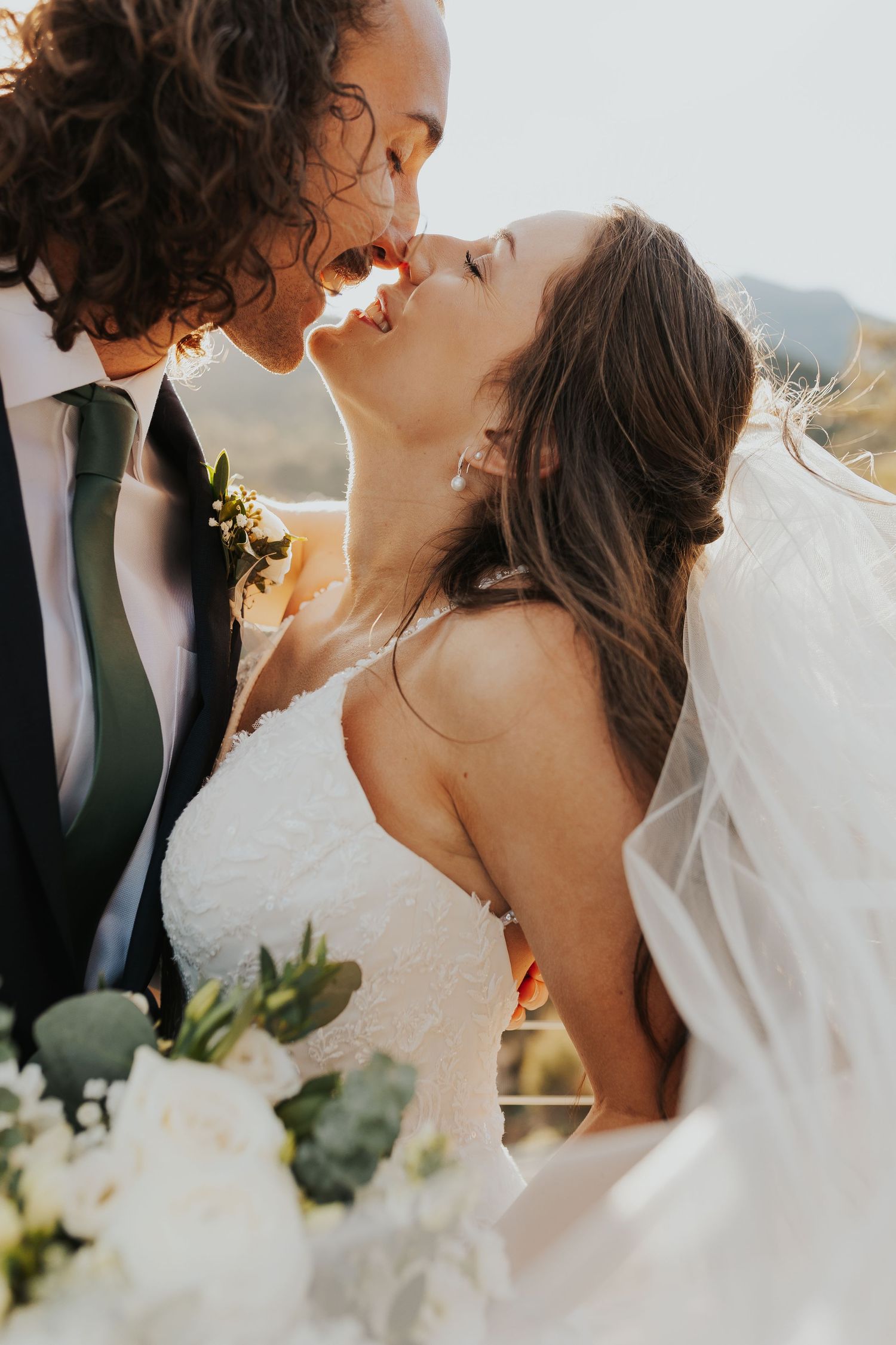 Bride and groom touching noses in the sunset
