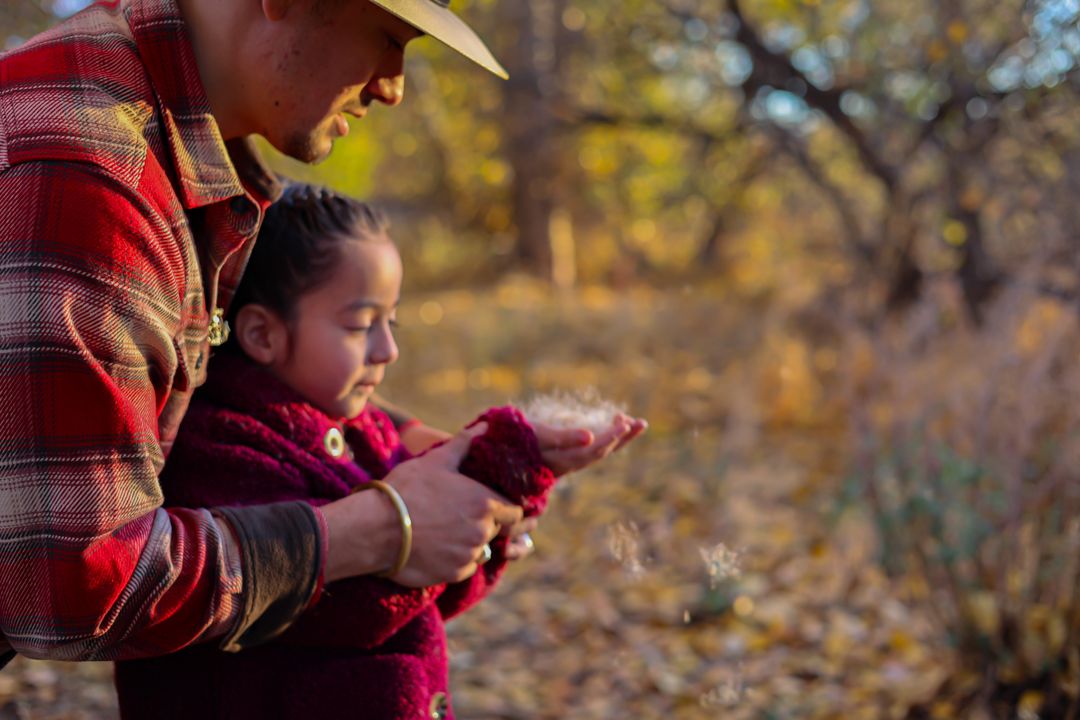 Adult and child exploring nature together on autumn day while wearing casual outdoor clothing.