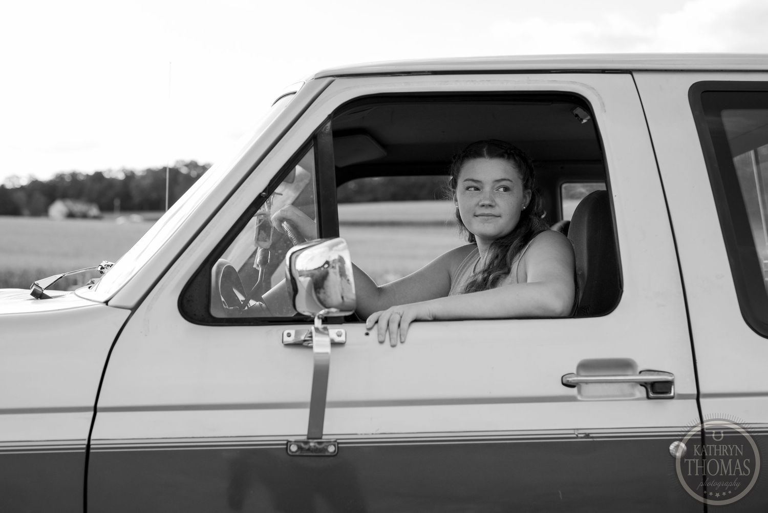 View through pickup truck window showing someone seated in driver's seat of vintage Ford truck.