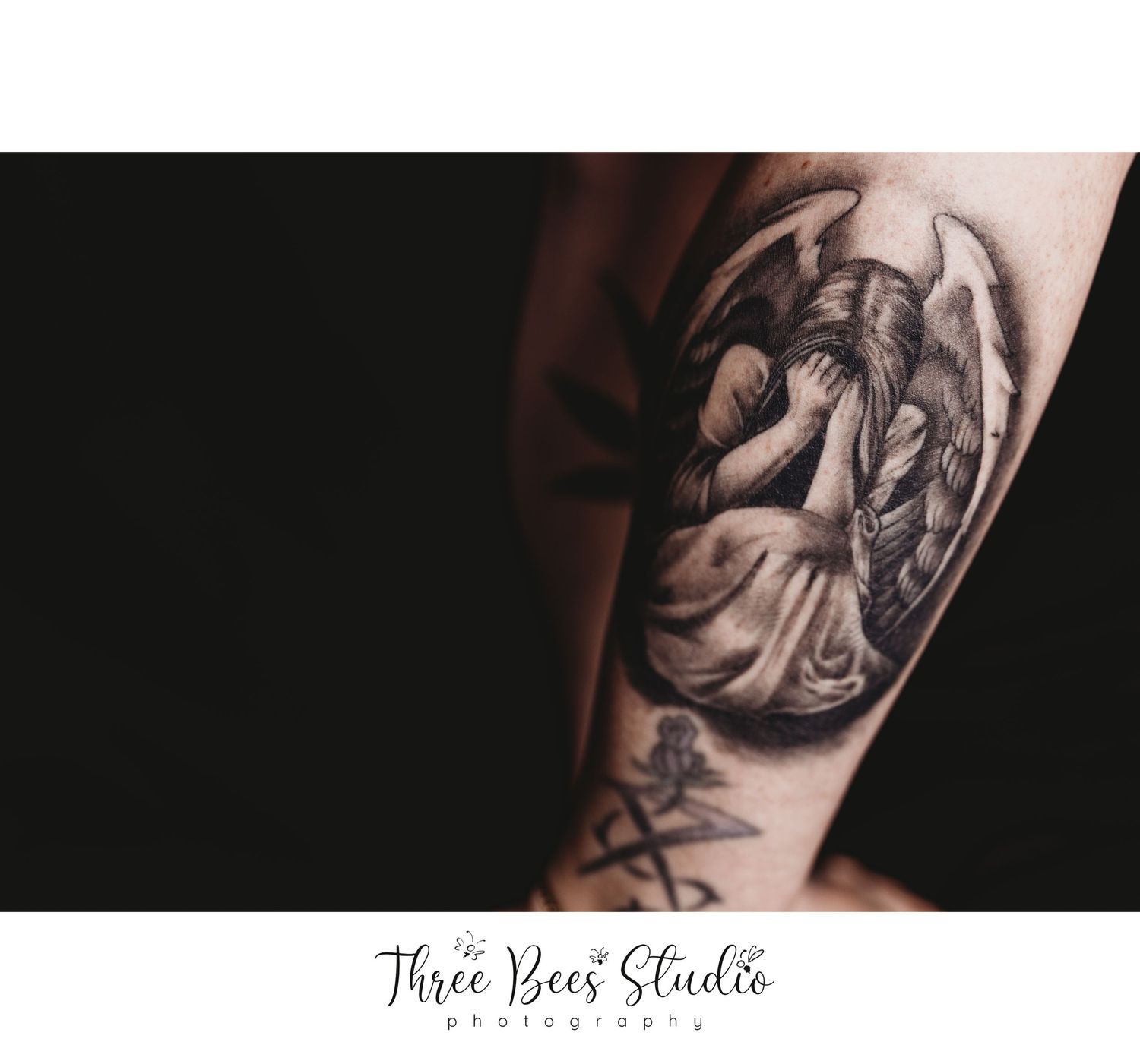 Detailed black and white tattoo of an angel on someone's arm.
