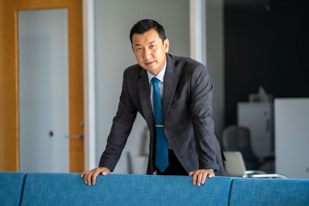 Business professional leaning on blue office furniture in corporate environment.