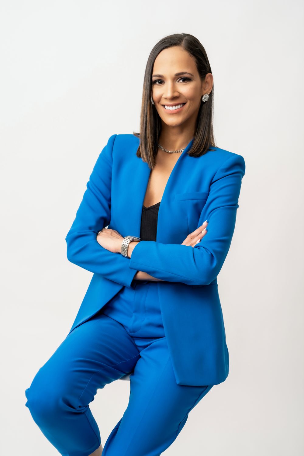 Confident pose in bright blue power suit against white studio backdrop.