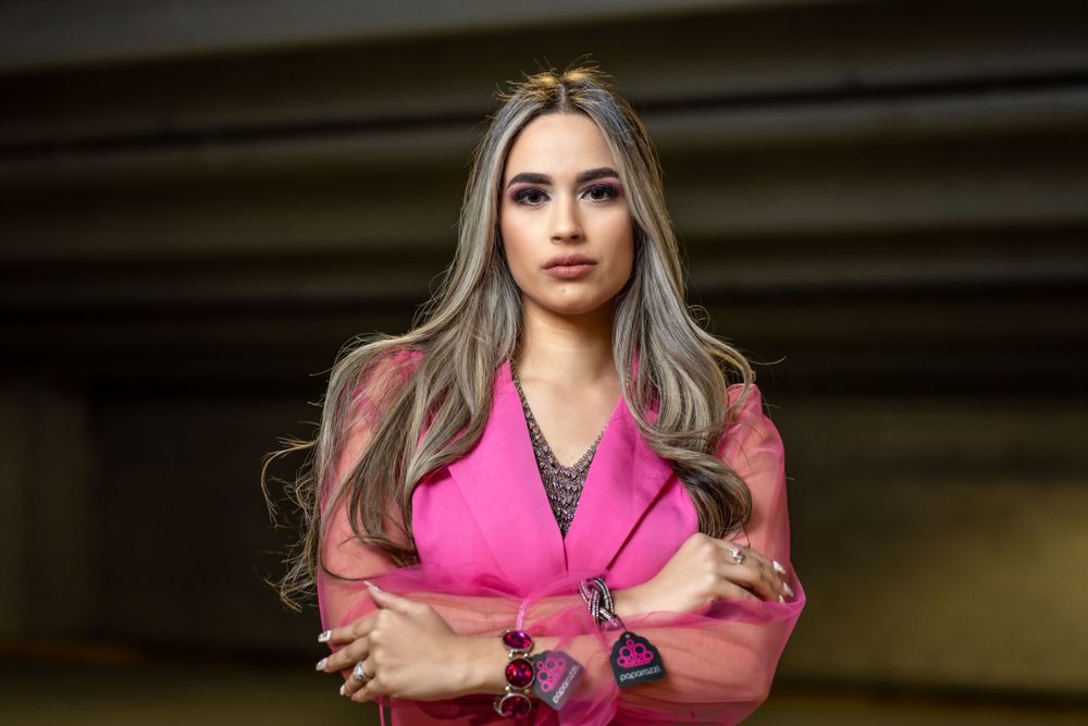 Portrait of a person in bright pink blazer against dark background.
