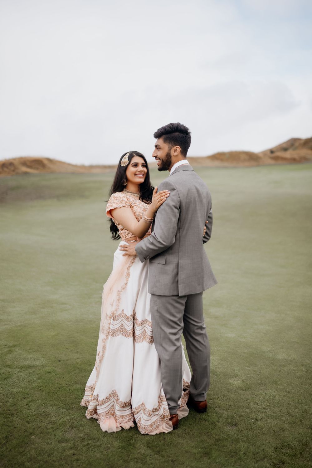 A romantic couple in formal attire embracing on a lush green golf course.